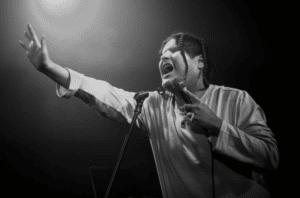 A black and white photo of a person singing into a microphone.