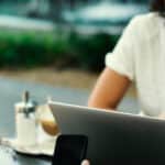 Two people sitting at a table with a laptop.