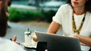 Two people sitting at a table with a laptop.