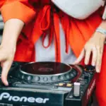 A woman in a red coat is holding a dj turntable.