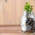 A DIY music funding project featuring a glass jar filled with coins and a plant.