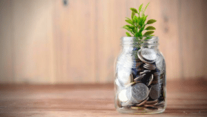 A DIY music funding project featuring a glass jar filled with coins and a plant.