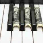 A piano keyboard with dollar bills on it.