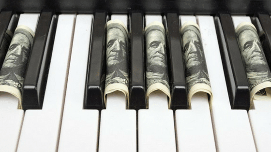 A piano keyboard with dollar bills on it.