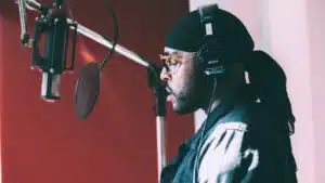 A man wearing a hat and headphones in a recording studio.