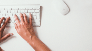 A woman's hands typing on a white keyboard.
