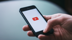 A person holding a phone with a youtube logo on it.