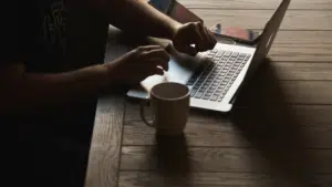 A man using a laptop on a wooden table.