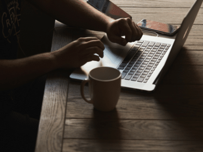 A man using a laptop on a wooden table.