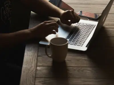 A man using a laptop on a wooden table.