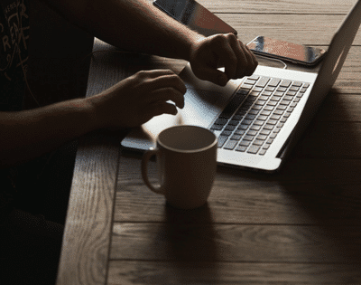 A man using a laptop on a wooden table.