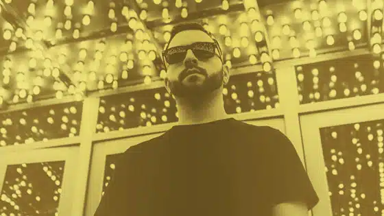 A man in sunglasses standing in front of lights.