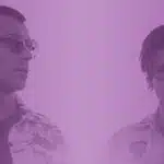 Two men standing in front of a purple background.