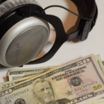A pair of headphones and some money on a table.