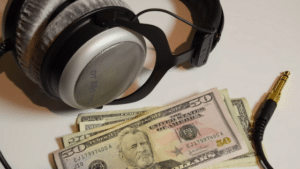 A pair of headphones and some money on a table.
