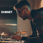 A man is working on a laptop in front of a dubset logo.