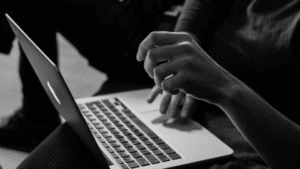 A black and white photo of a person using a laptop.