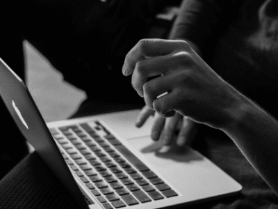 A black and white photo of a person using a laptop.