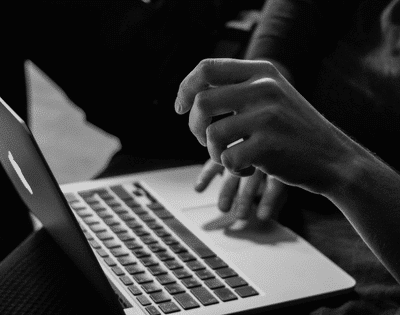 A black and white photo of a person using a laptop.