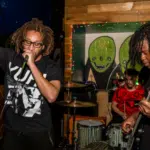 Two men with dreadlocks singing into a microphone.