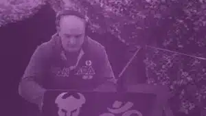 A man with headphones is playing music on a laptop.