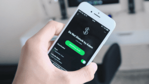 A person holding up a phone with the spotify app on it.