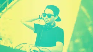 A dj wearing a hat and sunglasses in front of a green and yellow background.