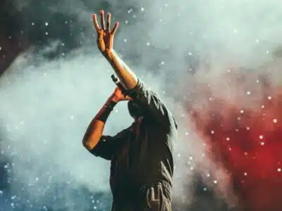 A man with his hands up in the air at a concert.