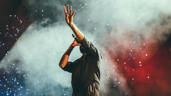 A man with his hands up in the air at a concert.