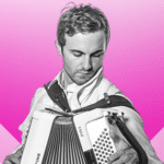 A man holding an accordion in front of a pink background.