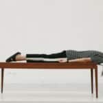 A woman laying on top of a wooden table.