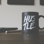 A black coffee mug with the word hustle on it.