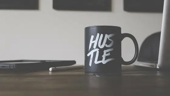 A black coffee mug with the word hustle on it.