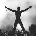 A man with his arms raised in the air at a concert.