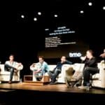 A group of men sitting on couches on a stage.