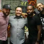 Four men posing for a photo in an office.