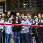 A group of people cutting a ribbon in front of a building.