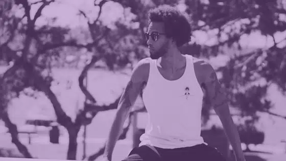 A man in a white tank top is sitting on a ledge.