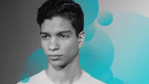 A young man in a white shirt with a blue background.