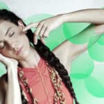 A woman with braided hair posing in front of a green background.