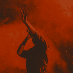 A silhouette of a man with his hands up in the air.