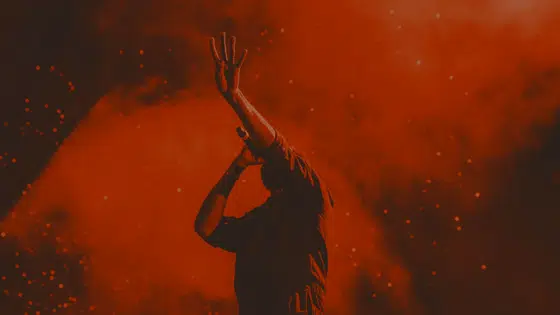 A silhouette of a man with his hands up in the air.