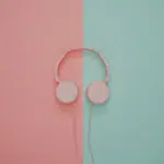 Pink headphones on a pink and turquoise wall.