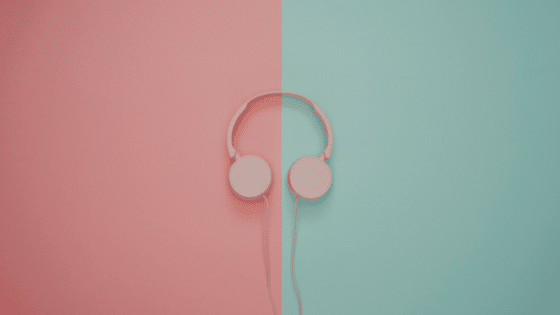 Pink headphones on a pink and turquoise wall.
