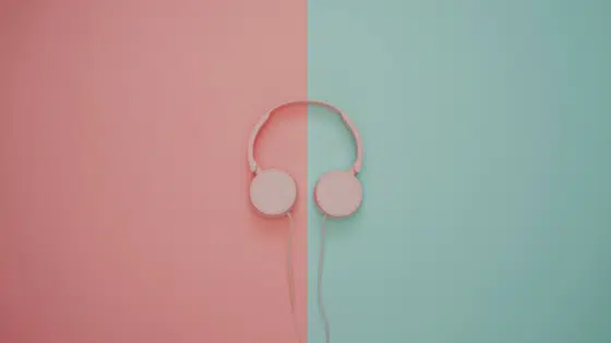 Pink headphones on a pink and turquoise wall.