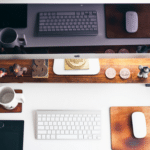 A desk with a monitor, keyboard, mouse and a cup of coffee.