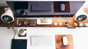 A desk with a monitor, keyboard, mouse and a cup of coffee.