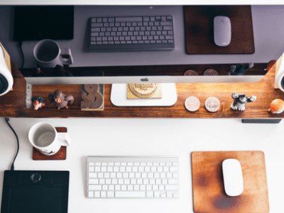 A desk with a monitor, keyboard, mouse and a cup of coffee.