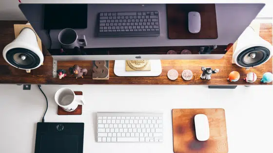 A desk with a monitor, keyboard, mouse and a cup of coffee.