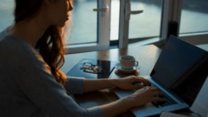 A woman working on her laptop in front of a window.